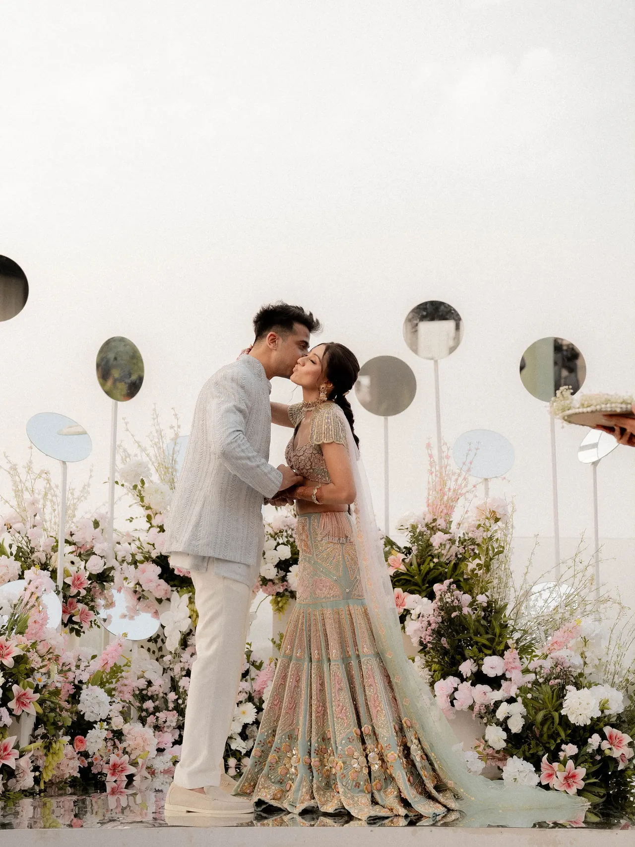 Pareja besándose ante una decoración floral en tonos rosa