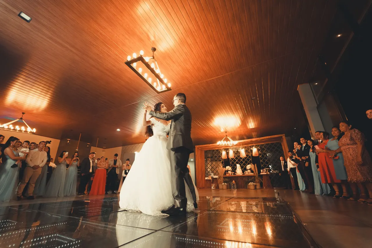 Primer baile de los novios en un salón con luz cálida y los invitados alrededor