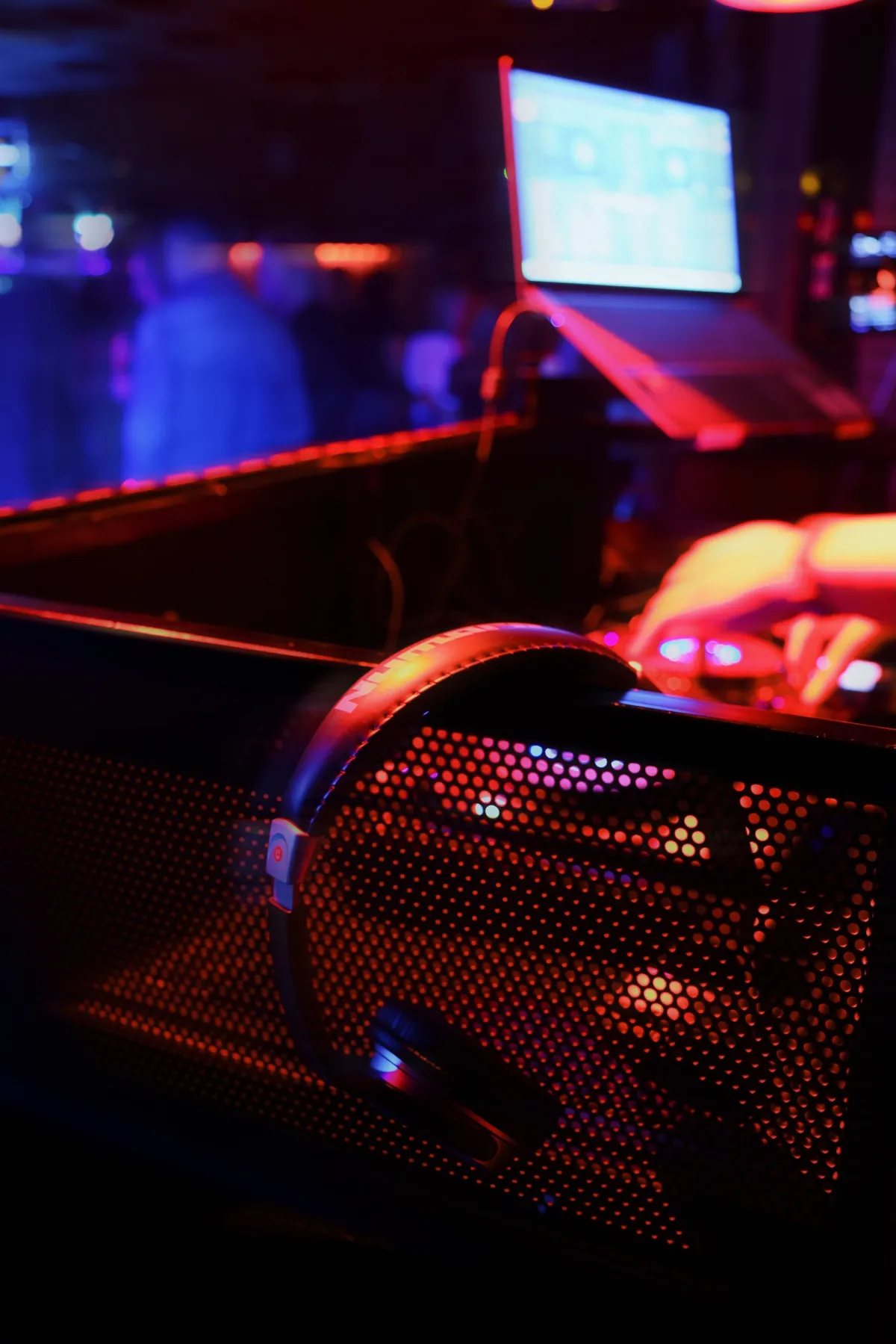 Auriculares de DJ sobre la cabina con el portátil y la pista de baile desenfocada al fondo